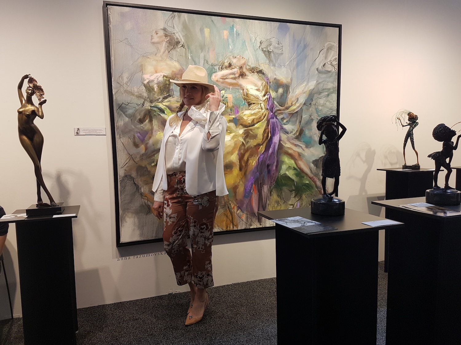 Anna in front of a large canvas with bronze sculptures