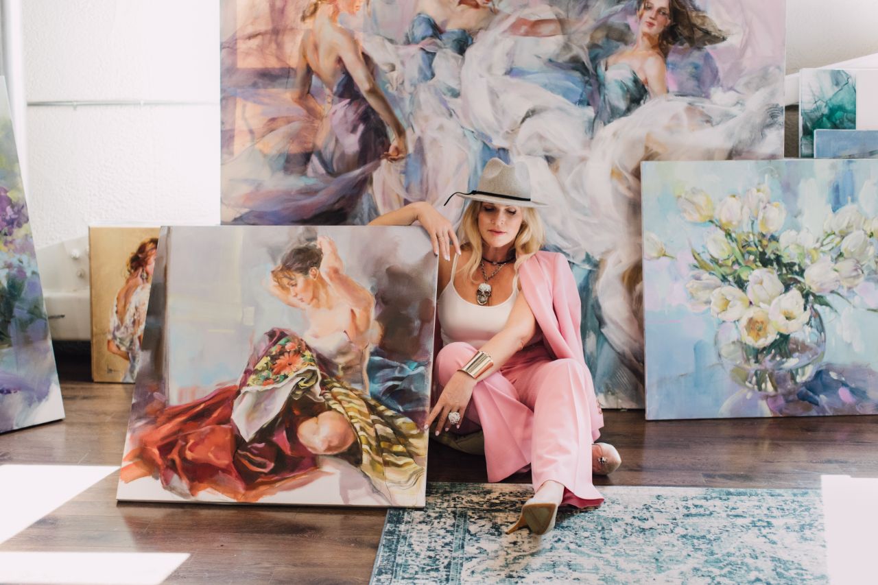 Anna Razumovskaya seated among finished canvases in the studio